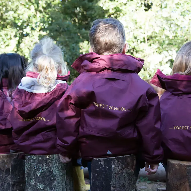 Nursery children sat in the forest school